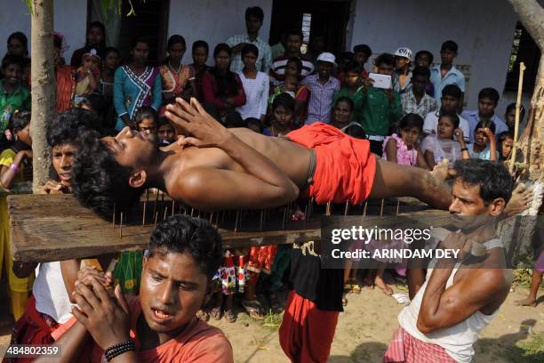 Hindu devotee lies on a bed of nails while fellow mates carry him past spectators during the ritual of Shiva Gajan at Pratapgarh village in Agartala,...