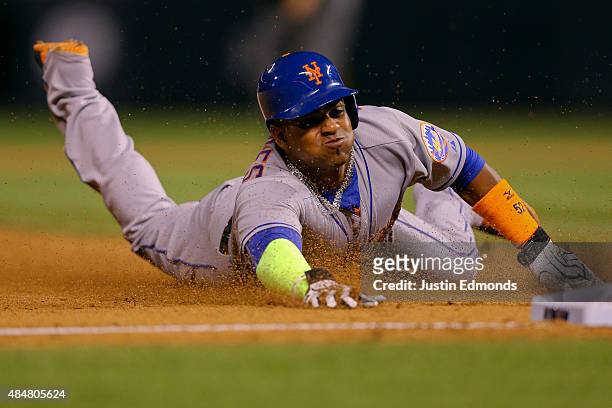 Yoenis Cespedes of the New York Mets slides into third with a stolen base during the eighth inning against the Colorado Rockies at Coors Field on...