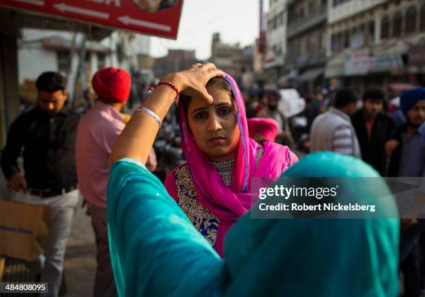 Hindu woman has a red bindi, or sindoor, applied by her mother February 23, 2014 in Amritsar, India.