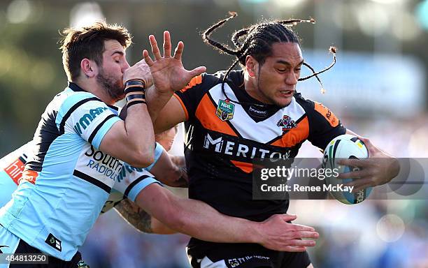 Martin Taupau of the Tigers fends off the tackle of Jack Bird of the Sharks during the round 24 NRL match between the Cronulla Sharks and the Wests...