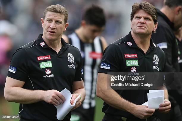 Magpies assistant coaches Scott Burns and Robert Harvey look up at the scoreboard at three quarter time during the round 21 AFL match between the...