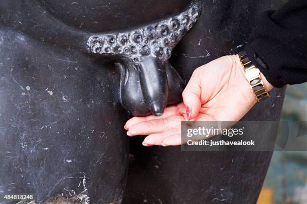 caucasian senior woman is placing hand at naked statue - phallic sculptures stock pictures, royalty-free photos & images