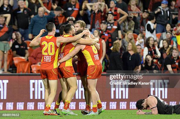 Tom Lynch of the Suns celebrates victory with team mates after the round 21 AFL match between the Gold Coast Suns and the Essendon Bombers at...