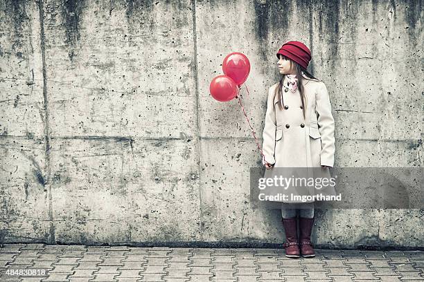 little girl with balloons standing by concrete wall - dented stock pictures, royalty-free photos & images