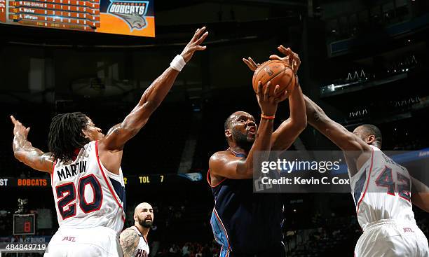 Al Jefferson of the Charlotte Bobcats shoots against Cartier Martin and Elton Brand of the Atlanta Hawks at Philips Arena on April 14, 2014 in...