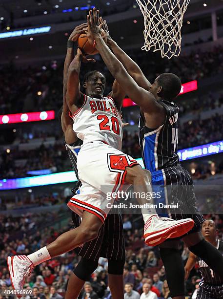 Tony Snell of the Chicago Bulls is fouled as he tries to shoot between Dewayne Dodmon and Andrew Nicholson of the Orlando Magic at the United Center...