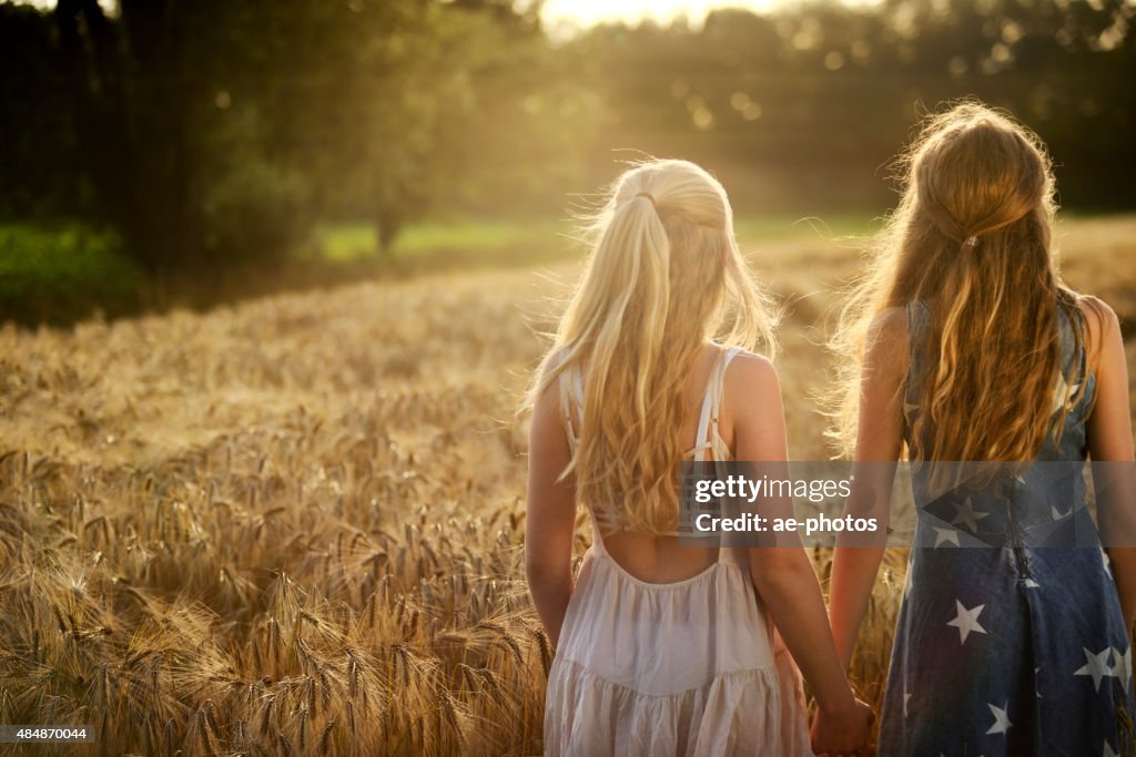 Due Ragazze adolescenti con le mani in un campo di orzo
