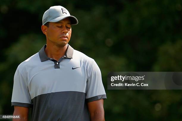 Tiger Woods reacts after missing his birdie putt on the 13th green during the third round of the Wyndham Championship at Sedgefield Country Club on...