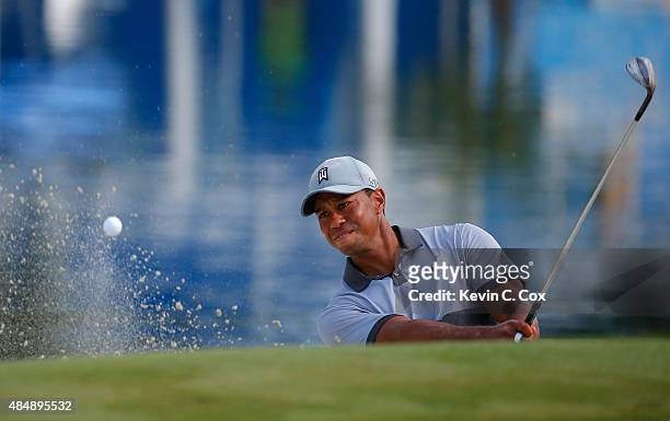 Tiger Woods chips out of the bunker on the 15th green during the third round of the Wyndham Championship at Sedgefield Country Club on August 22,...