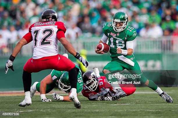Brett Smith of the Saskatchewan Roughriders scrambles and tries to avoid Juwan Simpson of the Calgary Stampeders in a game between the Calgary...