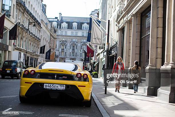 Members of the public walk past luxury goods retailers and a yellow Lamborghini on Old Bond Street on April 15, 2014 in London, England. A report by...