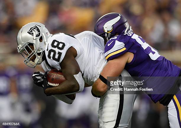 Chad Greenway of the Minnesota Vikings tackles Latavius Murray of the Oakland Raiders during the first quarter of the preseason game on August 22,...