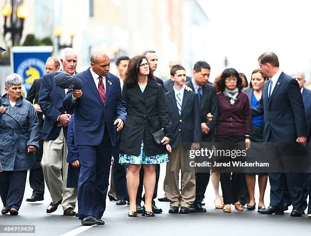 Massachusetts Governor Deval Patrick removes his hat during a wreath-laying ceremony with members of the victims families commemorating the one-year...