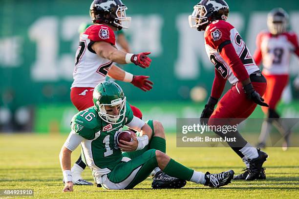 Brett Smith of the Saskatchewan Roughriders picks himself up after being sacked by two Calgary Stampeders in a game between the Calgary Stampeders...
