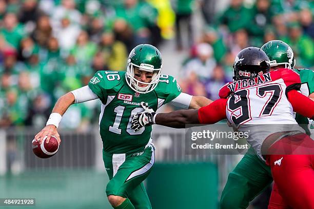 Brett Smith of the Saskatchewan Roughriders scrambles from the grasp of Derek Wiggan of the Calgary Stampeders in a game between the Calgary...