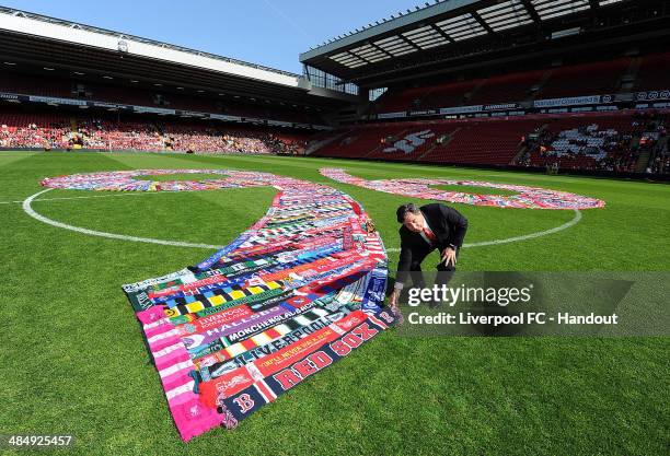 In this handout image provided by Liverpool FC, Tom Werner part owner of Liverpool lays a scarf down in the middle of the pitch during the memorial...