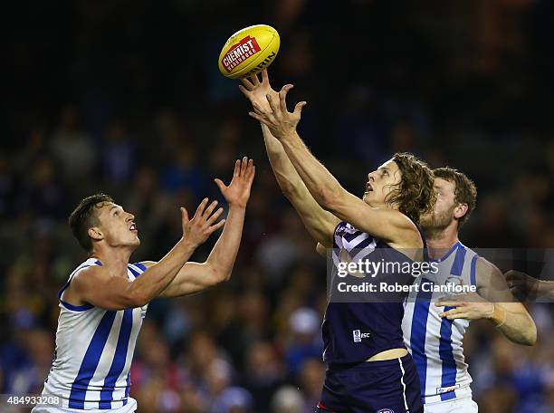 Nat Fyfe of the Dockers is challenged by Ben Jacobs and Lachlan Hansen of the Kangaros during the round 21 AFL match between the North Melbourne...