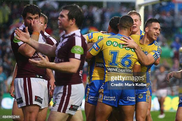 The Eels celebrate with Manu Ma'u of the Eagles after he scored a try during the round 24 NRL match between the Manly Warringah Sea Eagles and the...