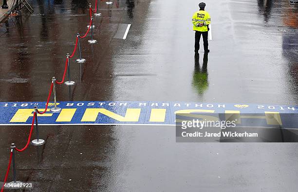 Boston Police officer stands guard at the finish line of the Boston Marathon prior to the flag raising ceremony commemorating the one-year...
