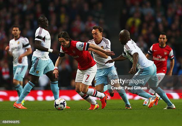 Tomas Rosicky of Arsenal evades Mark Noble and Pablo Armero of West Ham United during the Barclays Premier League match between Arsenal and West Ham...