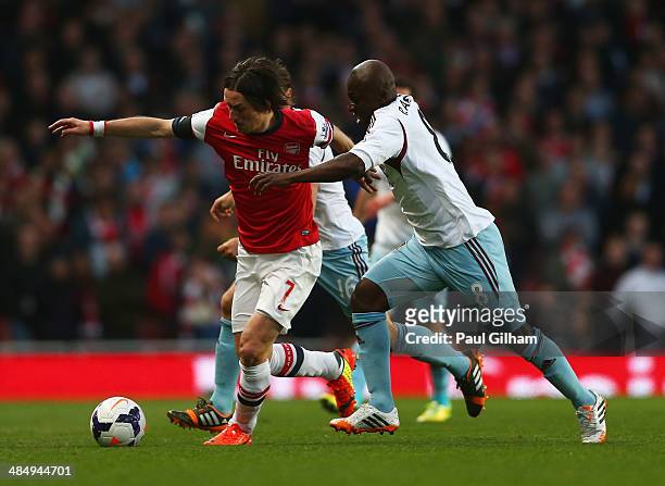 Tomas Rosicky of Arsenal evades Pablo Armero of West Ham United during the Barclays Premier League match between Arsenal and West Ham United at...