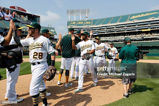 Eric Sogard, Marcus Semien and Brett Lawrie of the Oakland Athletics celebrate with teammates on the field following the game against the Houston...