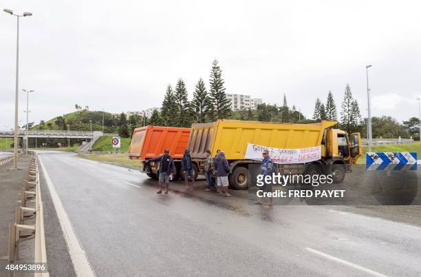 Photo taken on August 19, 2015 in Noumea shows trucks with a banner reading 'Gomez - Germain vendus, degagez - dehors' blocking the road, as truck...