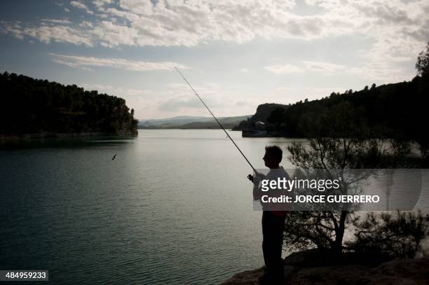 Men fish from the shores of Guadalorce dam in Ardales near Malaga on April 15, 2014. AFP PHOTO/ JORGE GUERRERO