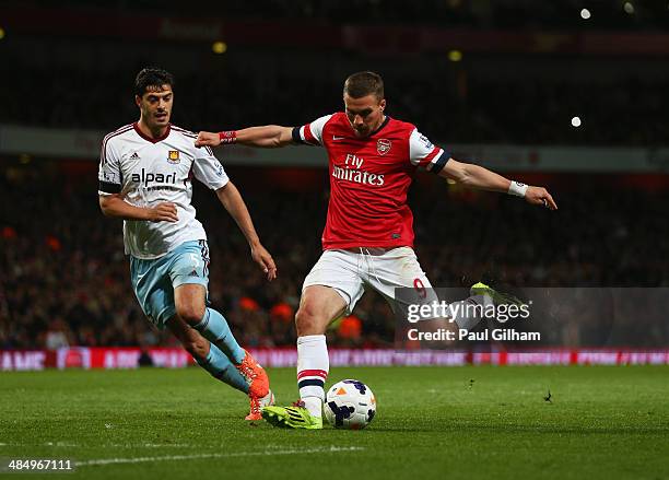 Lukas Podolski of Arsenal beats James Tomkins of West Ham United as he scores their third goal during the Barclays Premier League match between...