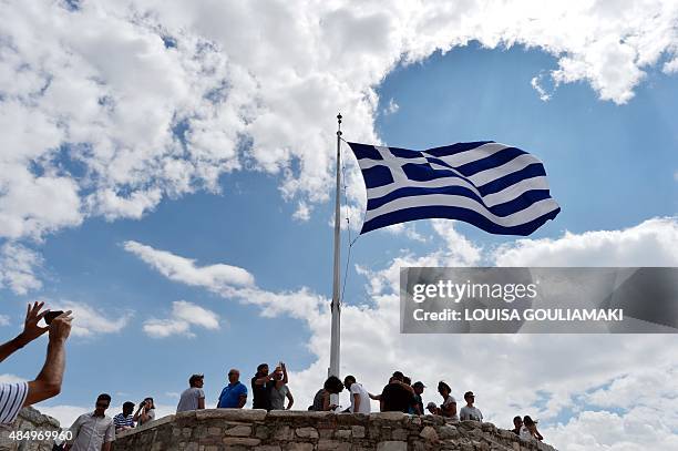 Man takes picture of a Greek flag atop the Acropolis archaeological site on August 23, 2015. Greek opposition parties try to form a coalition...