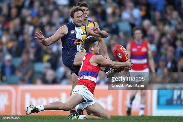 Luke Dahlhaus of the Bulldogs attempts to smother the kick by Mark Hutchings of the Eagles during the round 21 AFL match between the West Coast...