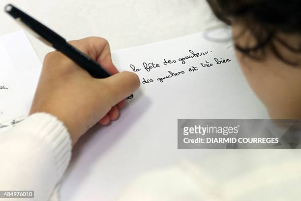 Left-handed child writes in the Salle du Pont du Buy in Brive-la Gaillarde, where writing and cooking workshops were organised and objets for the...