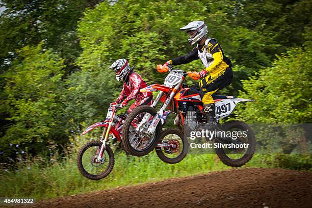 les coureurs de motocross se air sur un saut en course - motocross photos et images de collection