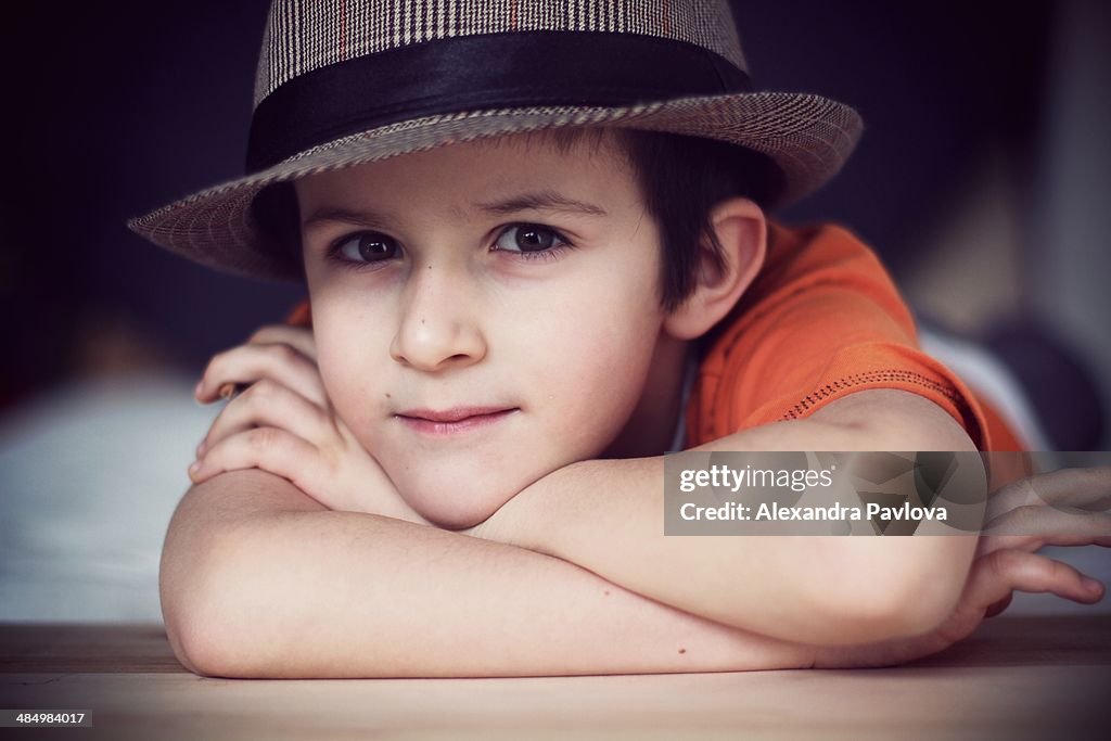 Cute boy with hat, relaxed, propping chin on hands