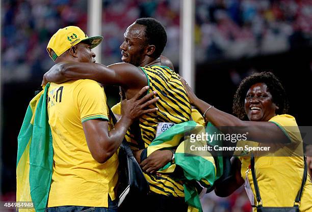 Usain Bolt of Jamaica celebrates with mother Jennifer Bolt and father Wellesley Bolt after winning gold in the Men's 100 metres final during day two...