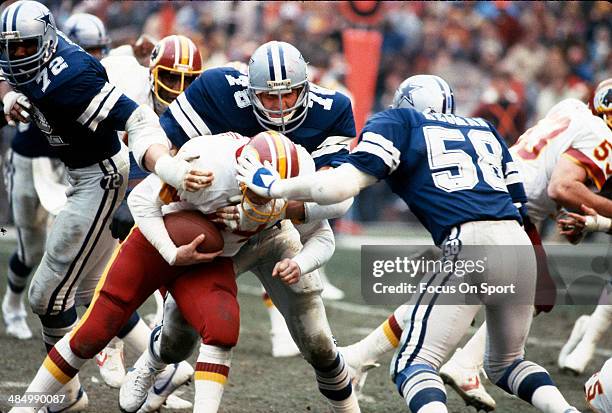 John Dutton and Mike Higman of the Dallas Cowboys tackles John Riggins of the Washington Redskins during an NFL Football game circa 1982 at RFK...