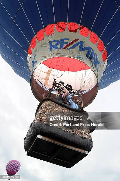 Karen Girardin of Lewiston and Brenda Grondin of Durham wave to the crowd as they rise up fast in the Re/Max balloon piloted by Chris Mooney at the...