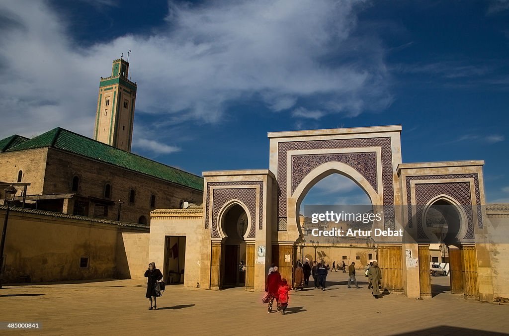 Fez medina gate with people and green mosque
