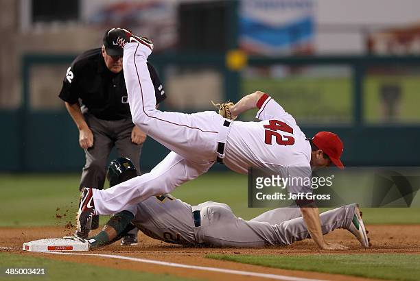 Third baseman David Freese of the Los Angeles Angels of Anaheim falls over Yoenis Cespedes of the Oakland Athletics after tagging him out as he was...