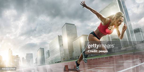 woman athlete sprinting in wet city - startblok atletiek stockfoto's en -beelden
