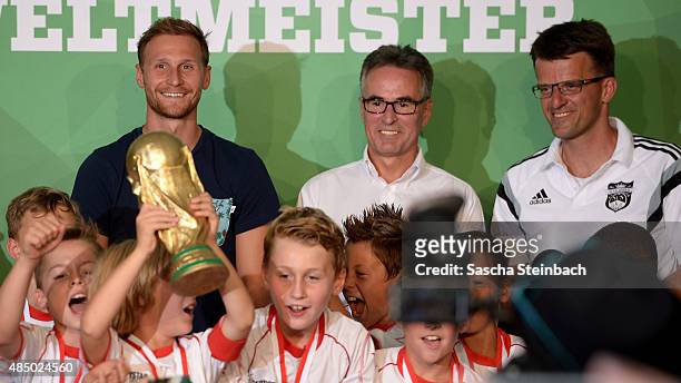 Kids celebrate with the trophy as Benedikt Hoewedes and Helmut Sandrock look on during the closing event of the 'DFB Ehrenrunde' on August 23, 2015...