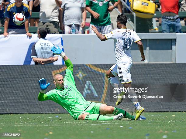 Giovani Dos Santos of Los Angeles Galaxy kicks the ball over goalkeeper Josh Saunders of New York City FC to score a goal during the second half at...