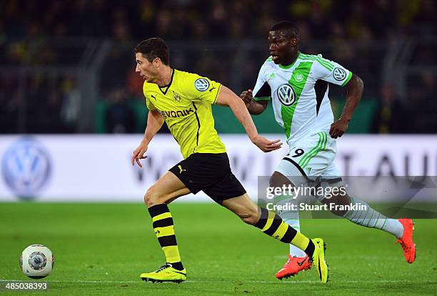 Robert Lewandowski of Dortmund is challenged by Bernard Malanda-Adje of Wolfsburg during the DFB Cup semi final match between Borussia Dortmund and...