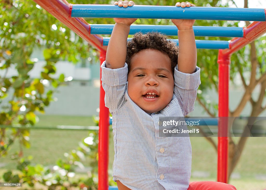 Child holding on to monkey bars