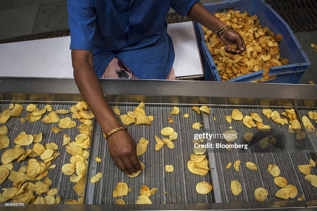 A worker sorts fried crinkle-cut potato chips as they move along a News  Photo - Getty Images