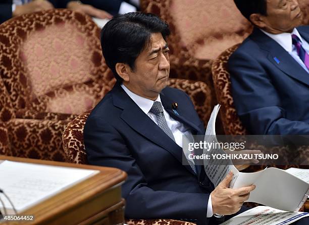 Japanese Prime Minister Shinzo Abe listens to a question by an opposition lawmaker at the Upper House's budget committee session at the National Diet...