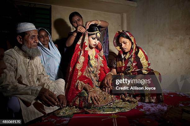 Year old Nasoin Akhter sits with relatives while posing for photos on the day of her wedding to a 32 year old man, August 20, 2015 in Manikganj,...