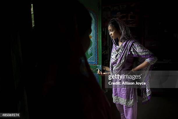 Year old Mousammat Akhi Akhter stands in the doorway of her home August 19, 2015 in Manikganj, Bangladesh. Last year, when she was only 13, Akhi got...