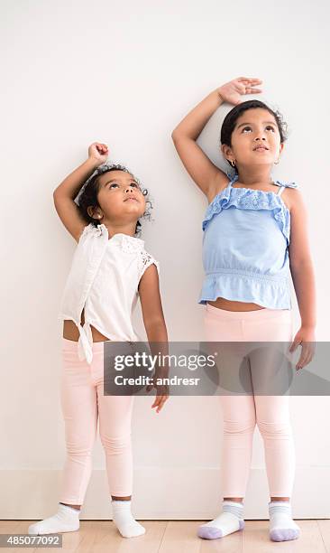 girls checking how tall theyâve grown - lang lichaamslengte stockfoto's en -beelden