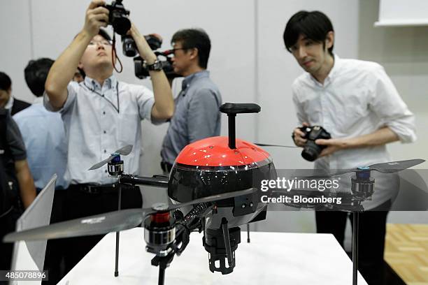 Members of the media take photographs of an AS-MC01-P multicopter unmanned aerial vehicle , developed by Aerosense Inc., a joint venture between Sony...